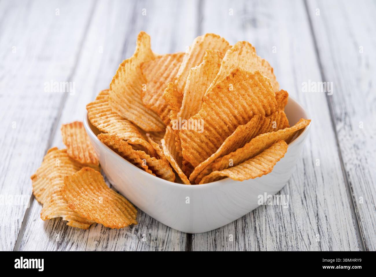 Porzione di increspata Patatine (messa a fuoco selettiva) su un vecchio tavolo in legno Foto Stock