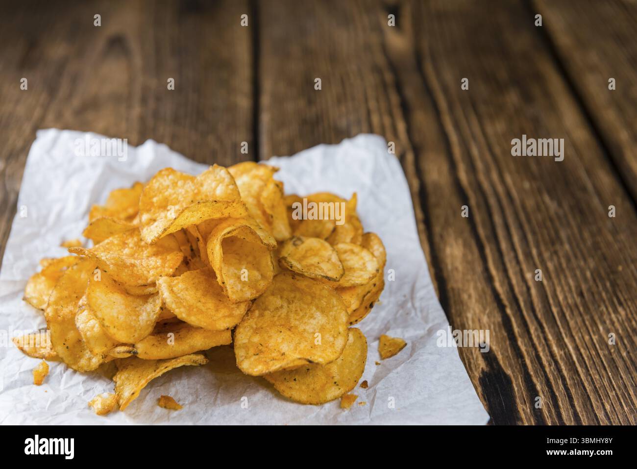 Cumulo di Chili Potato Chips (messa a fuoco selettiva) su un vecchio tavolo in legno Foto Stock