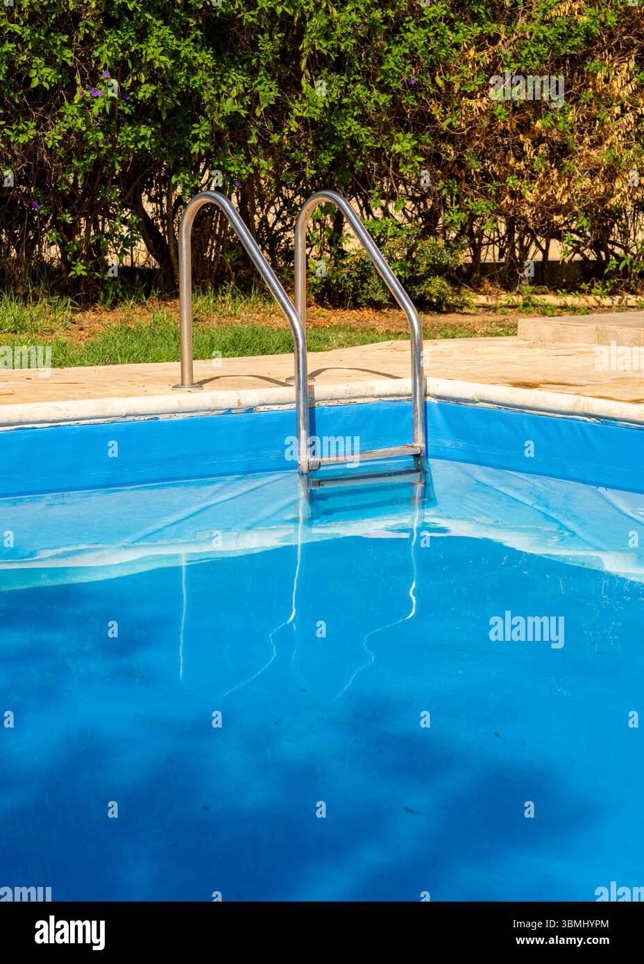 Scala metallica per piscine che conduce a calme acque turchesi. Ambiente estivo pulito e minimalista, perfetto per resort, vacanze, spa o temi di design benessere. Foto Stock