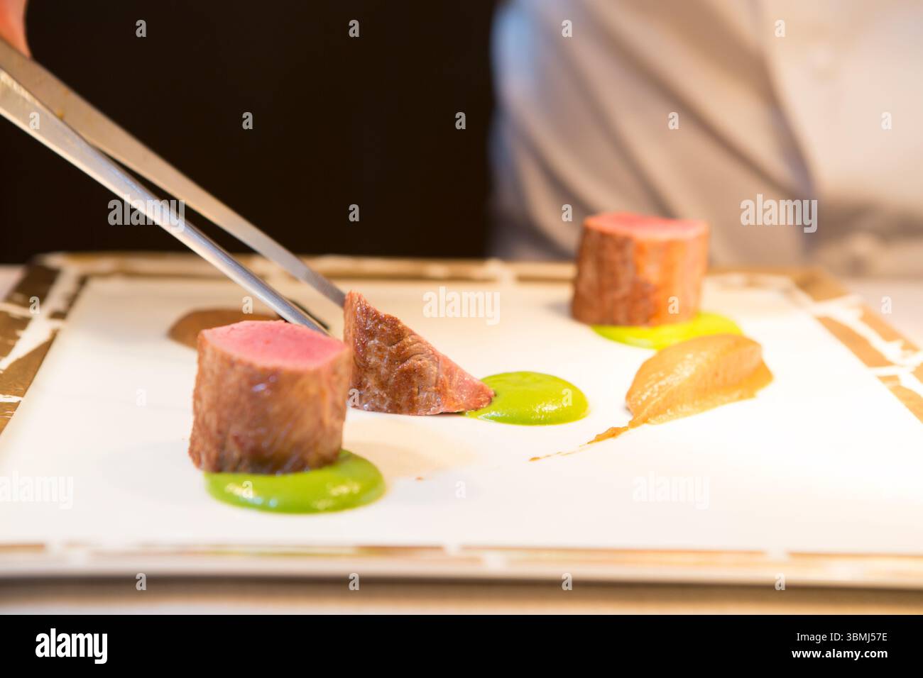 Uno chef semina sapientemente teneri filetti di manzo Foto Stock
