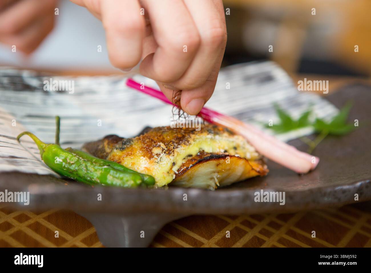 Uno chef prepara con cura gli ingredienti per un piatto raffinato, utilizzando le tradizionali ciotole in ceramica Foto Stock