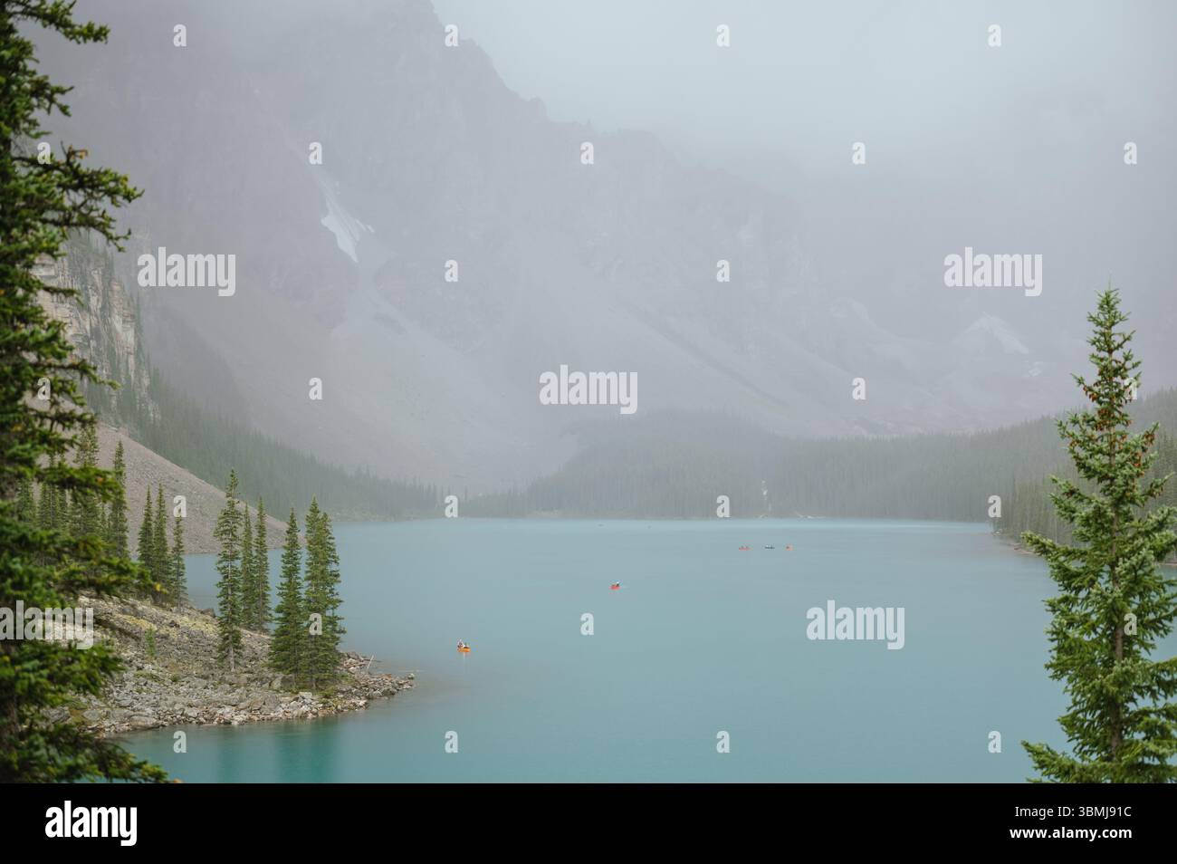 I turisti fanno canoa sul lago Moraine calmo e piovoso a Banff, Canada Foto Stock