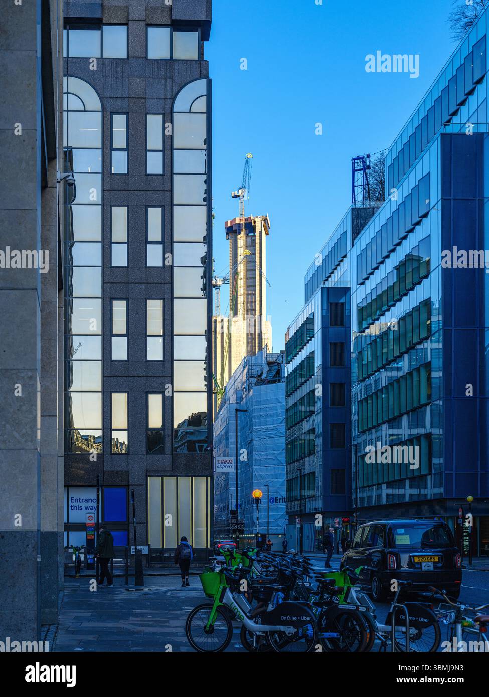 Regno Unito, Londra, 30 giugno 2025. I lavoratori della città e i ciclisti delle consegne si riuniscono di fronte ai moderni uffici nell'area di Farringdon, vicino a Smithfield Foto Stock