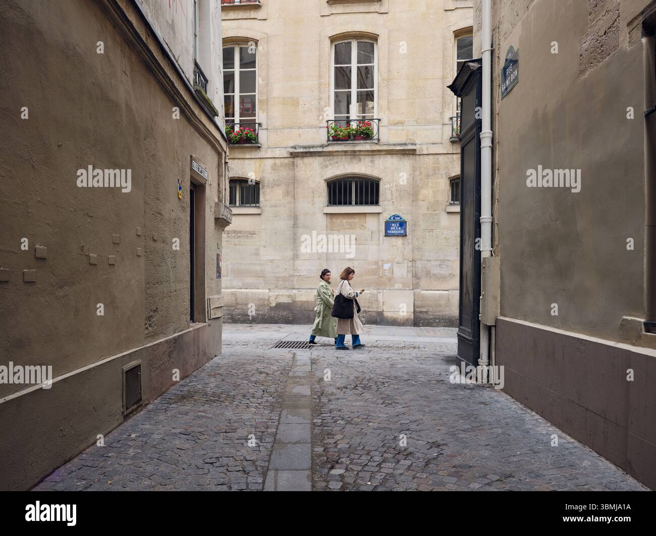 Due donne che camminano lungo una stretta strada acciottolata a parigi Foto Stock