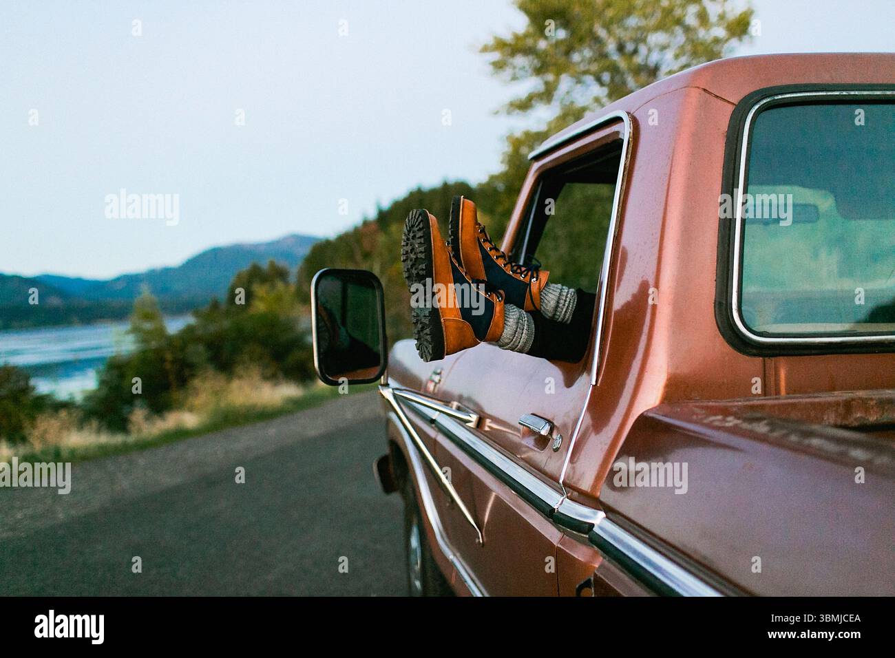 Piedi con stivali appesi fuori da un pick-up Foto Stock