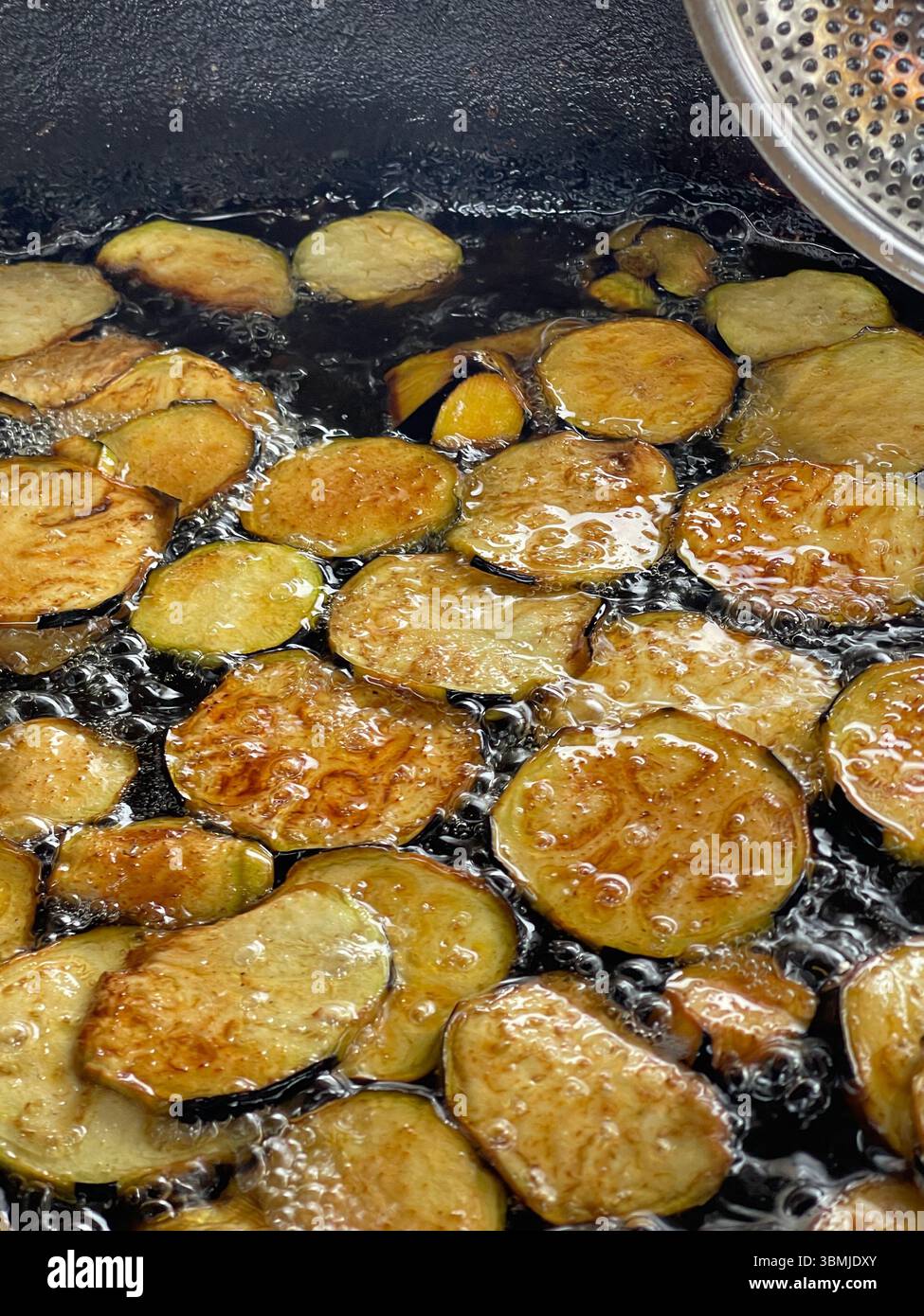 Friggere le fette di melanzane nell'olio, popolare cibo di strada. Foto Stock