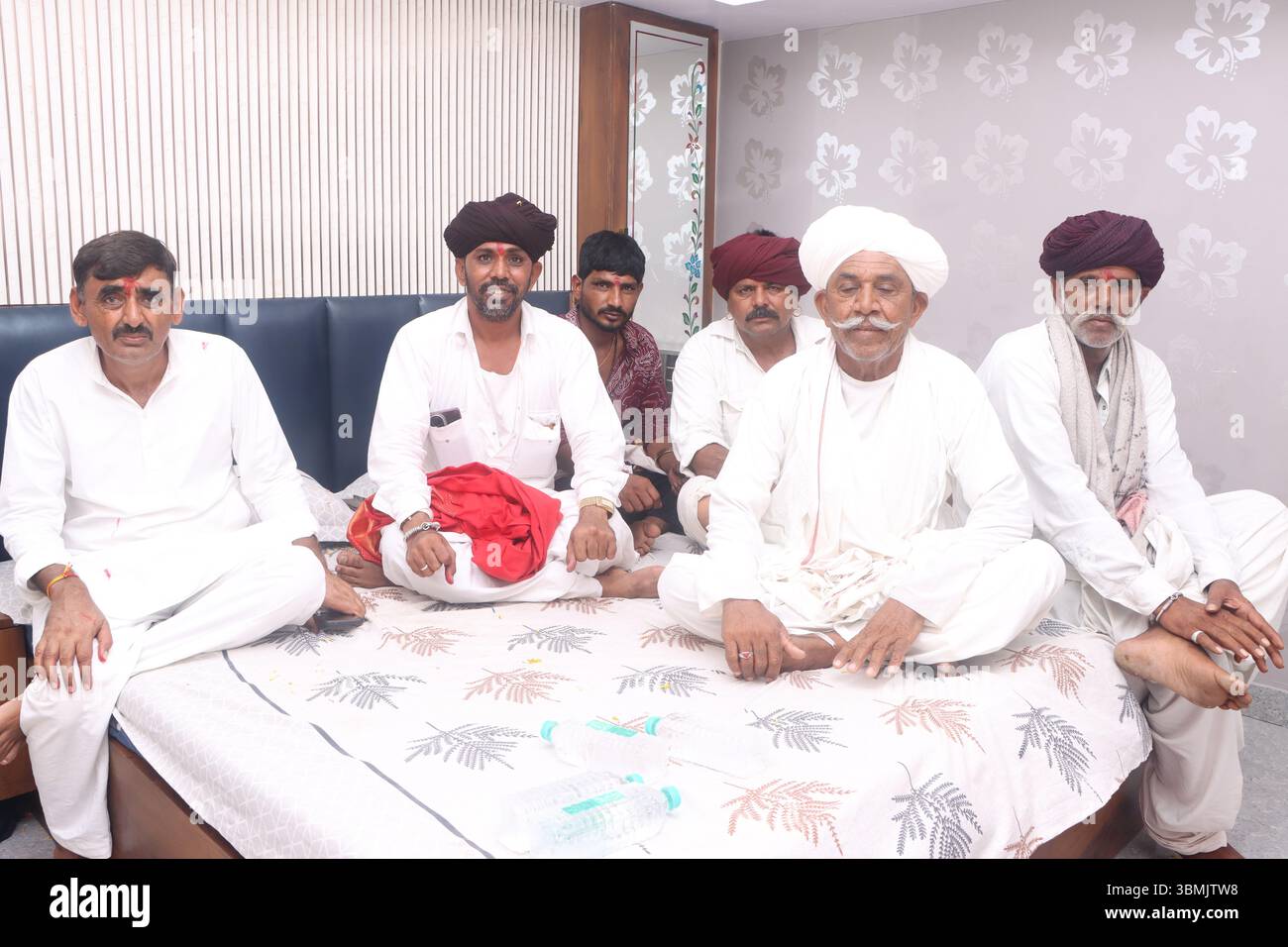 Gruppo di uomini indiani rurali in abbigliamento tradizionale seduti al chiuso durante una riunione della comunità Foto Stock