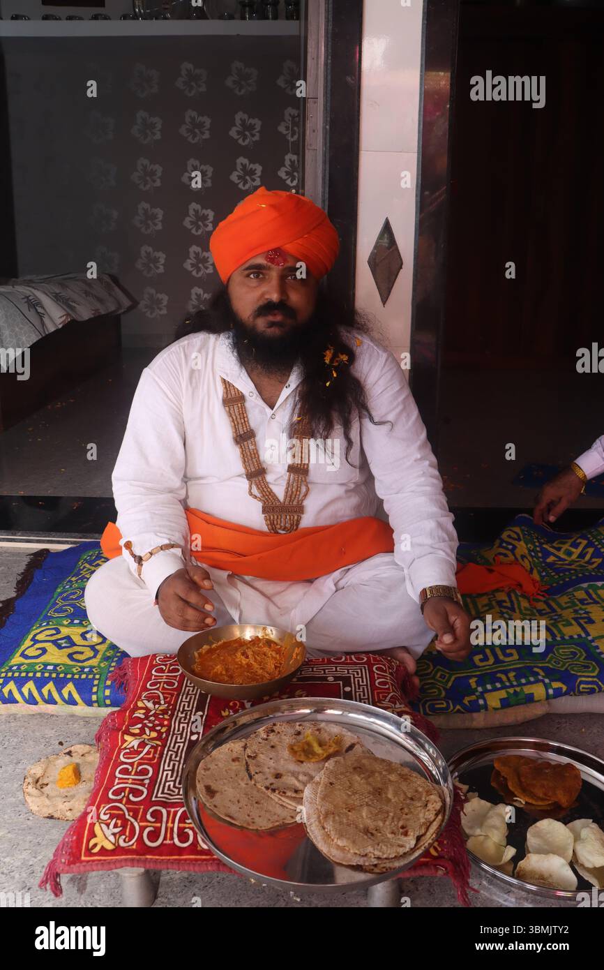 Uomo indiano che gioca a dhol tradizionale durante una cerimonia culturale Foto Stock