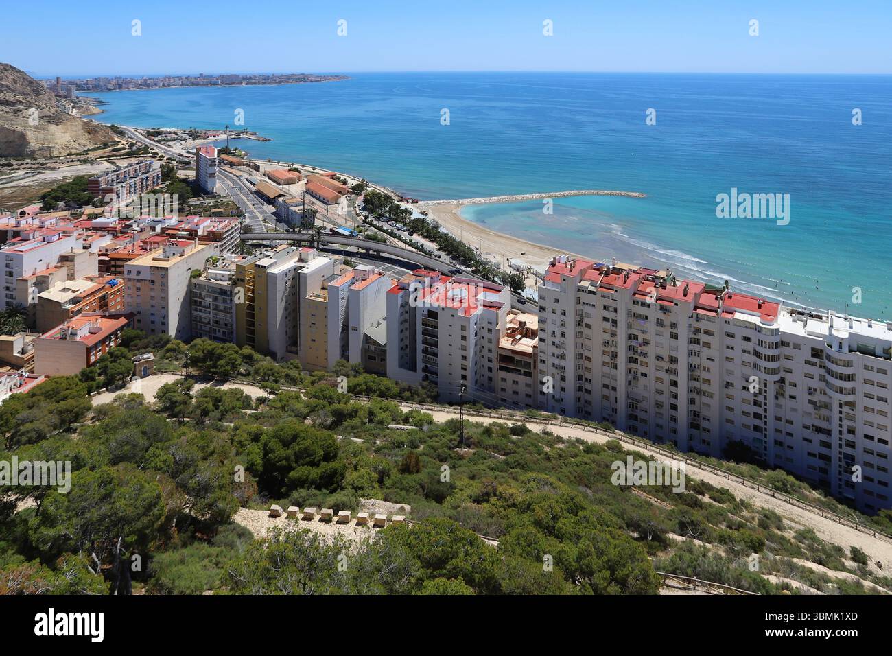 Vista costiera della spiaggia di Postiguet ad Alicante con mare blu, hotel moderni, palme e lungomare. Foto Stock