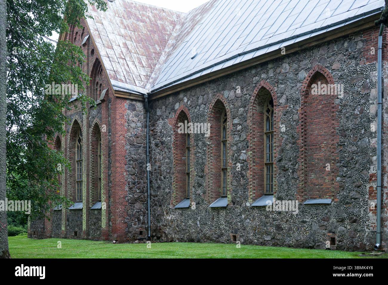 Storica chiesa in pietra con finestre in stile gotico e dettagli in mattoni nell'Estonia rurale, Äksi Foto Stock