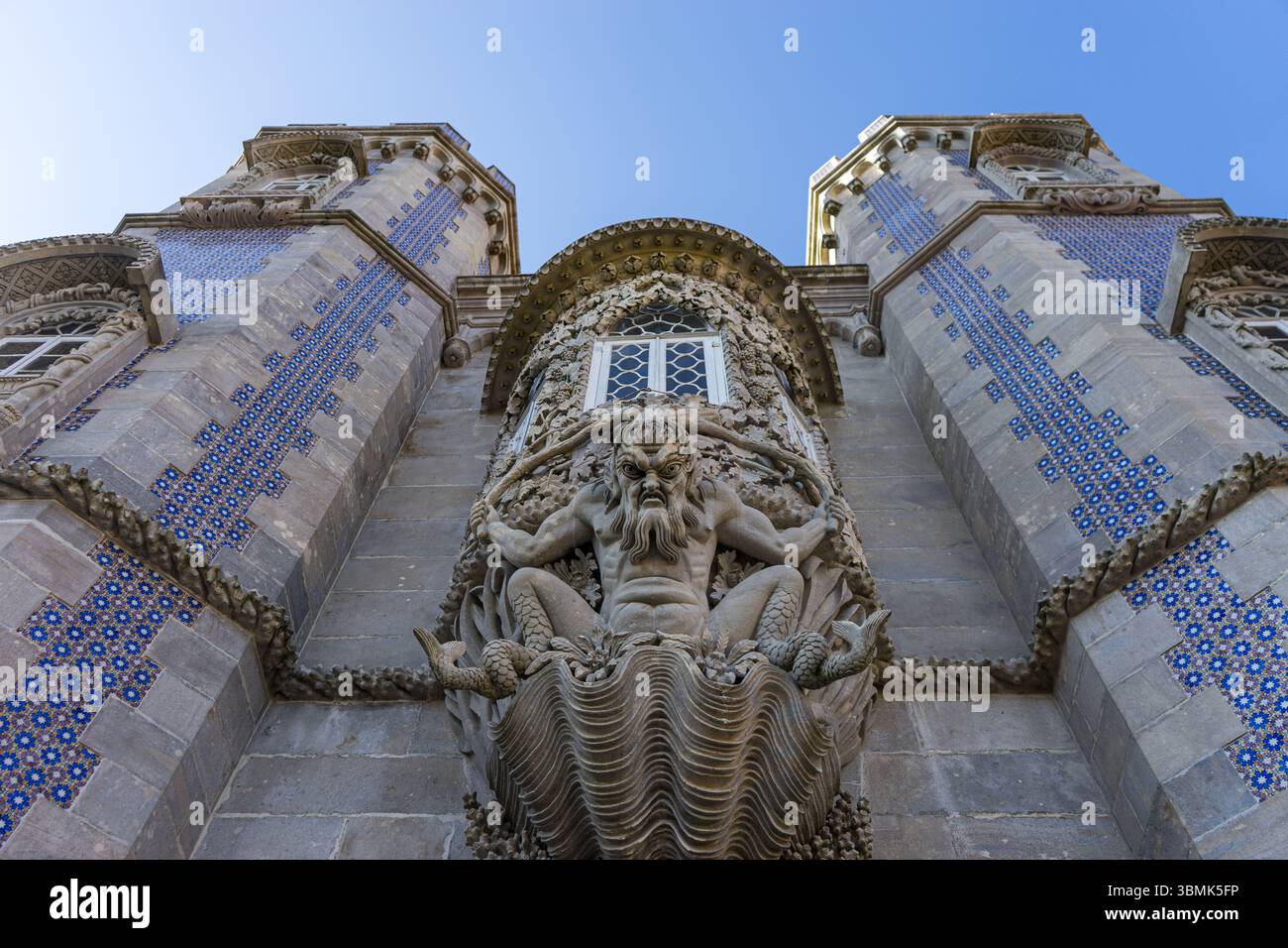 Vista dettagliata della porta ornata del Tritone al Palácio da pena, Sintra, Portogallo: Scultura mitologica e dettagli architettonici su un cielo limpido. Foto Stock