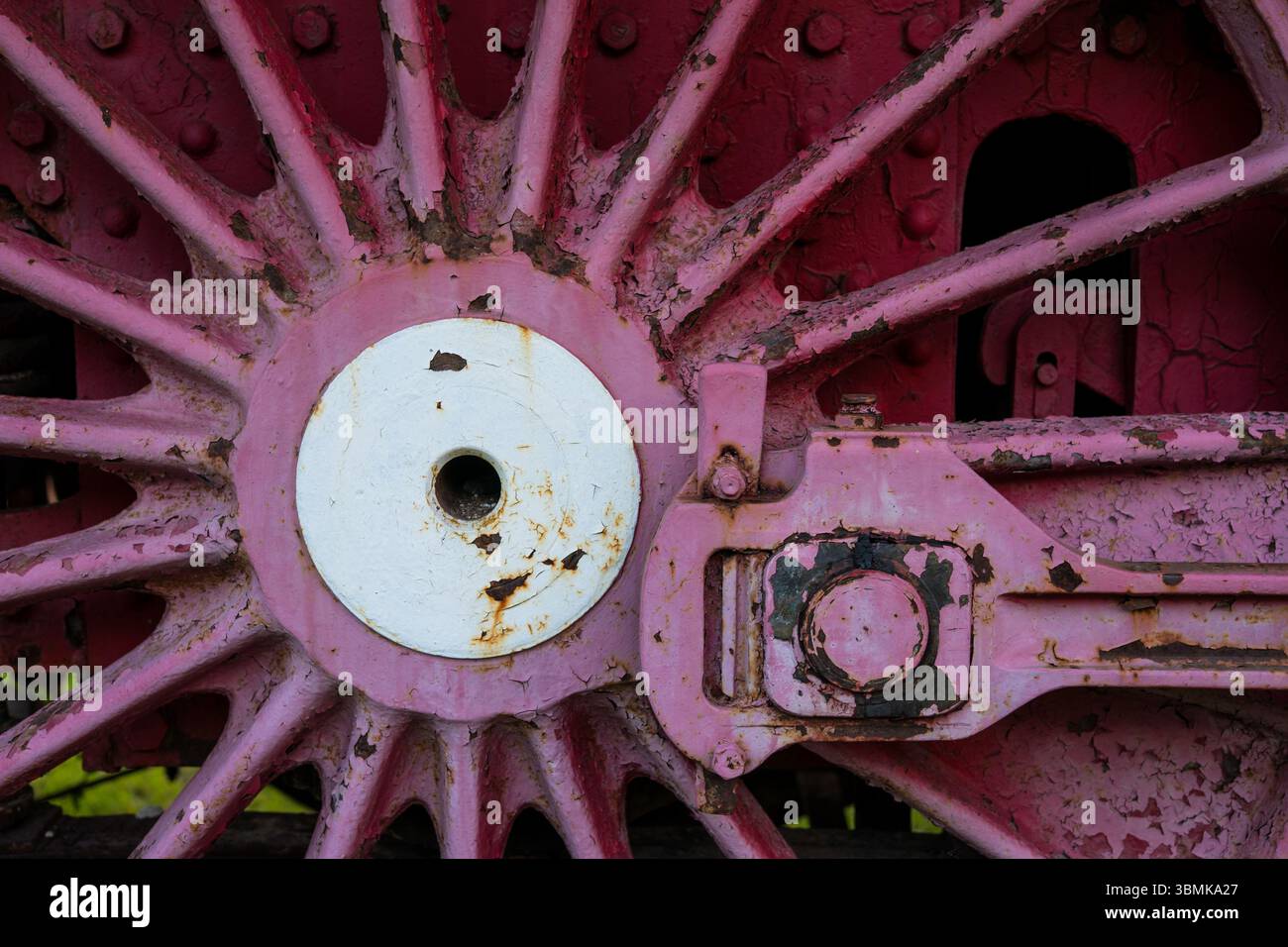 Dettaglio di una ruota rossa arrugginita con centro bianco, sfondo industriale Foto Stock