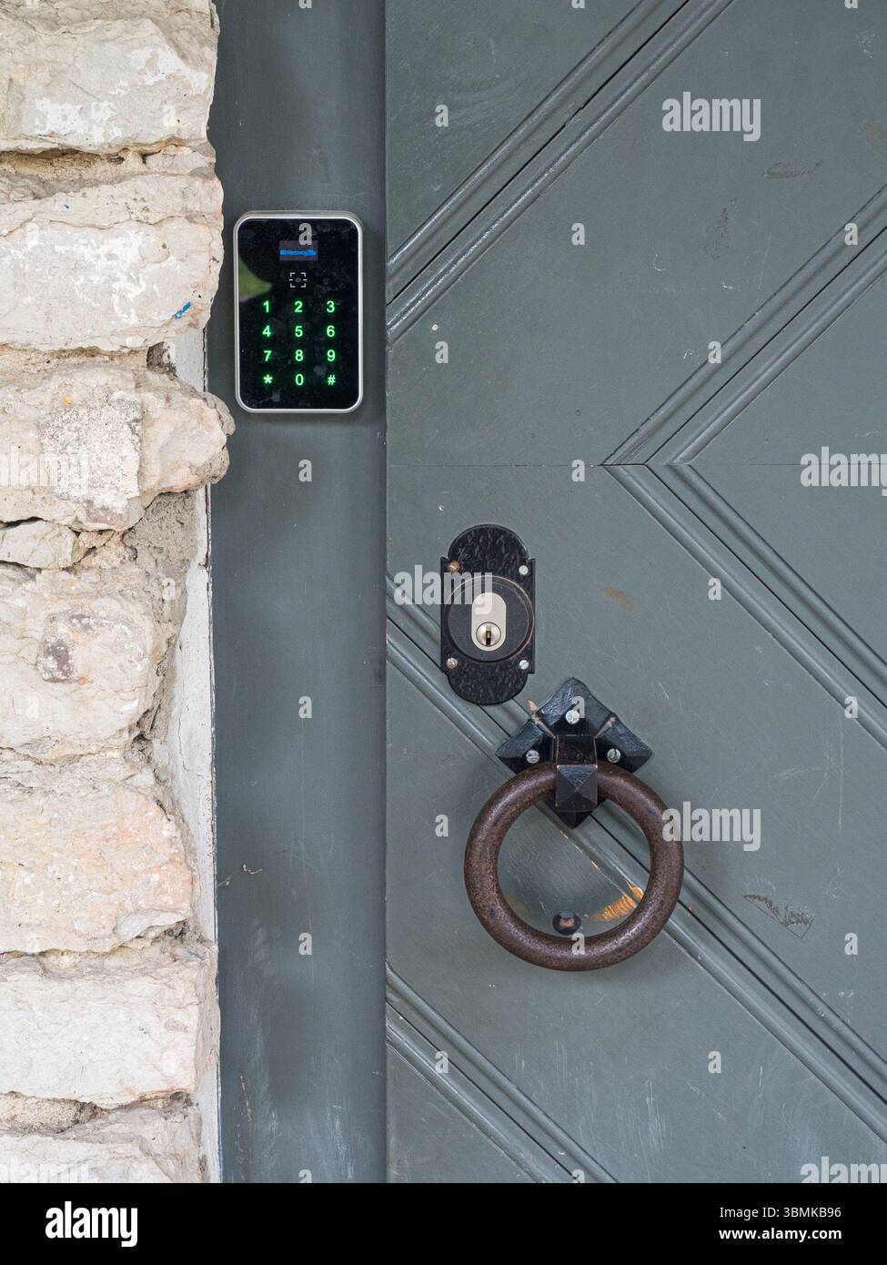 Moderna serratura elettronica con tastiera e porta d'epoca bussata su un edificio storico in pietra, concetto di sicurezza e tecnologia, Estonia. Foto Stock