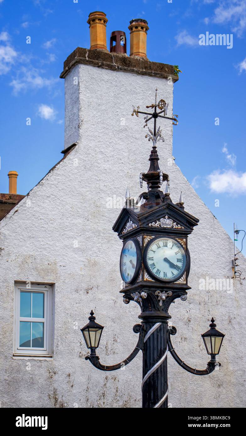 L'orologio della città di Ullapool, giustapposto a un edificio vicino, si trova contro la pila di camini Foto Stock