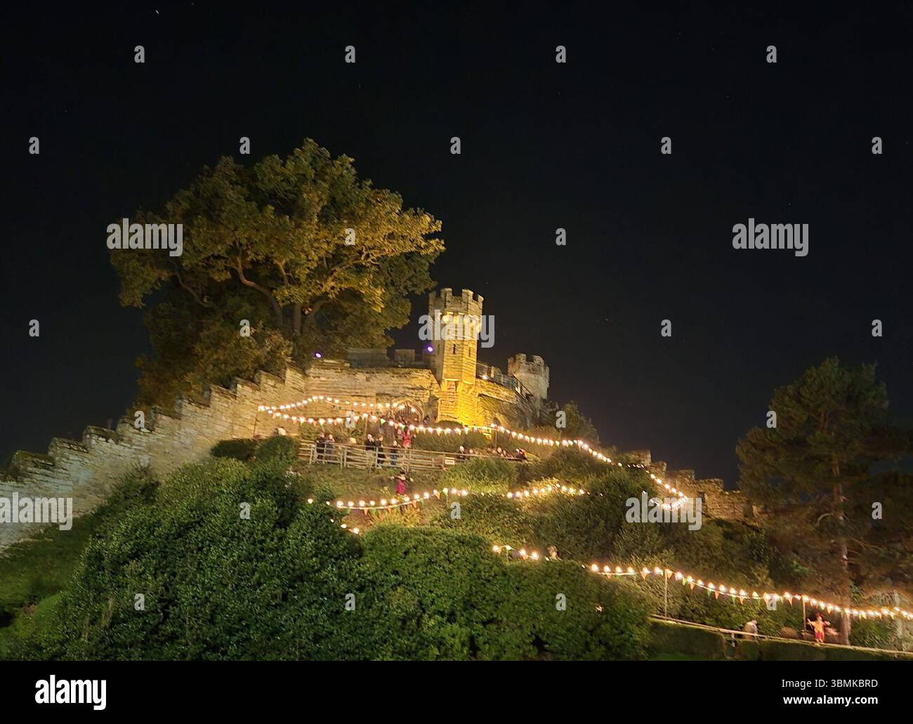 Vista notturna delle mura e delle torri medievali illuminate al castello di Warwick durante un evento serale all'aperto a Warwick, in Inghilterra. Foto Stock