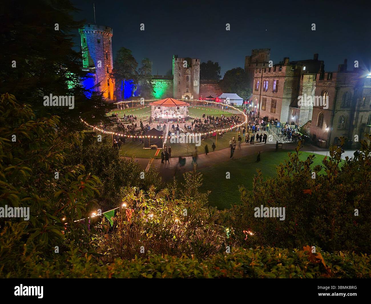 Vista notturna in stile aereo dei giardini illuminati del castello di Warwick durante un evento serale all'aperto a Warwick, in Inghilterra. - Immagine stock catturata con smartphone