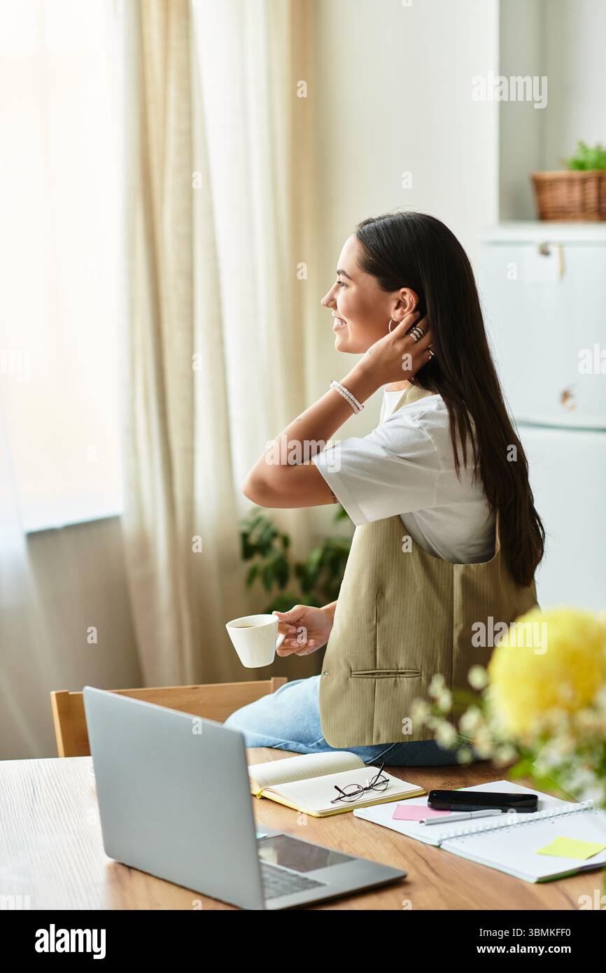 Una bella giovane donna siede comodamente a casa, riflettendo sulla sua giornata con un drink caldo in mano. Foto Stock