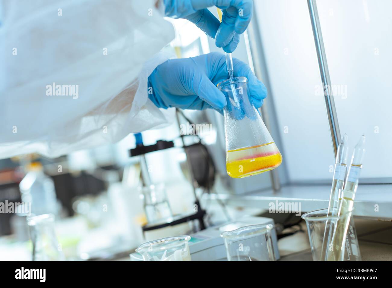 Lo scienziato esegue test di laboratorio e controlli di qualità del campione di olio utilizzando una pipetta in un moderno centro di ricerca Foto Stock