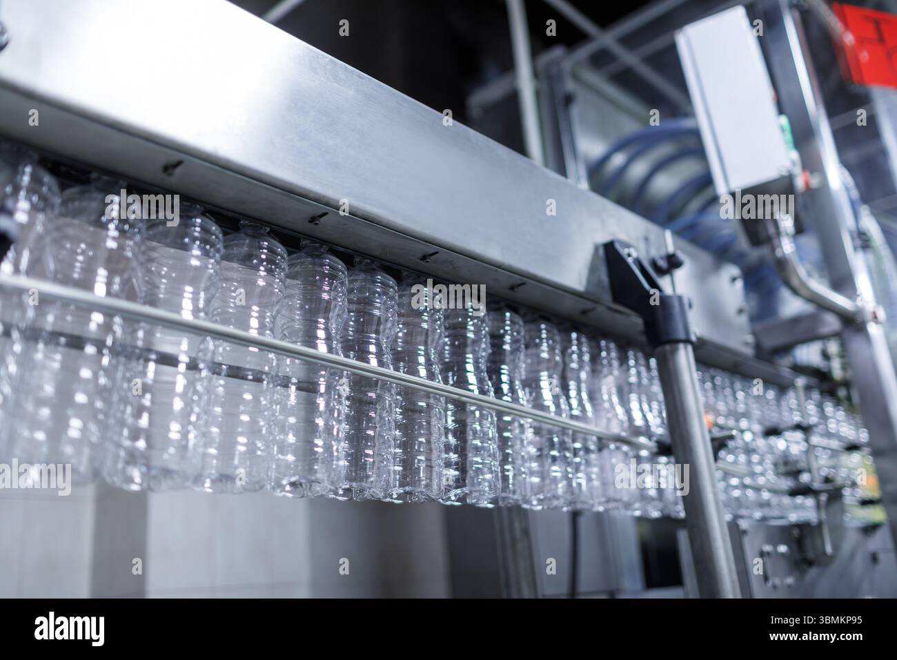 Linea di produzione di bottiglie in plastica in una fabbrica moderna con contenitori vuoti su trasportatore automatizzato pronto per il riempimento Foto Stock