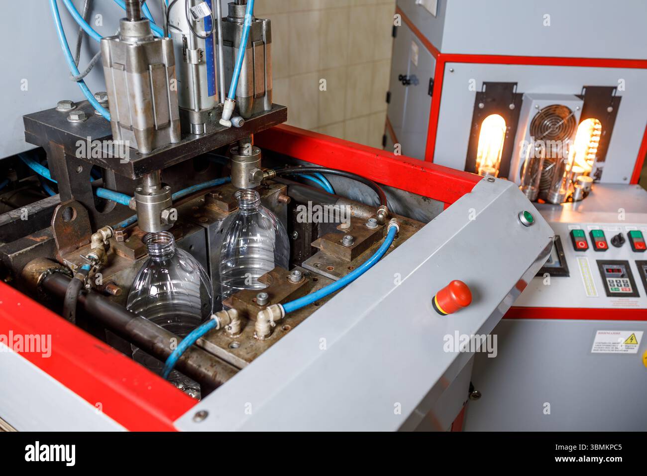 Linea di produzione di bottiglie in plastica con pressa per soffiaggio e controlli automatici in una moderna fabbrica industriale Foto Stock