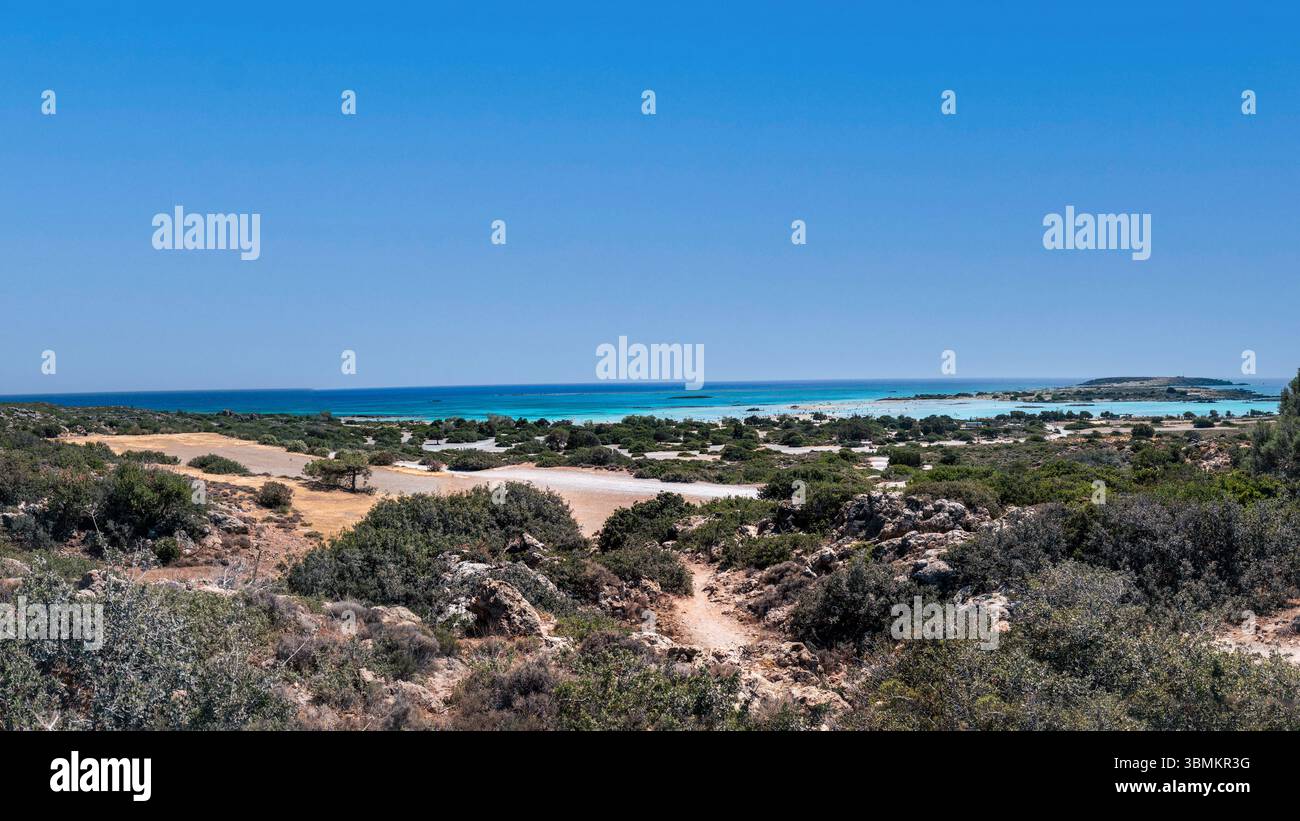 Ampio panorama 16:9, affacciato sulla famosa laguna di Elafonissi a Creta, in Grecia. Il vivace mare turchese contrasta con la secca macchia mediterranea sotto a. Foto Stock