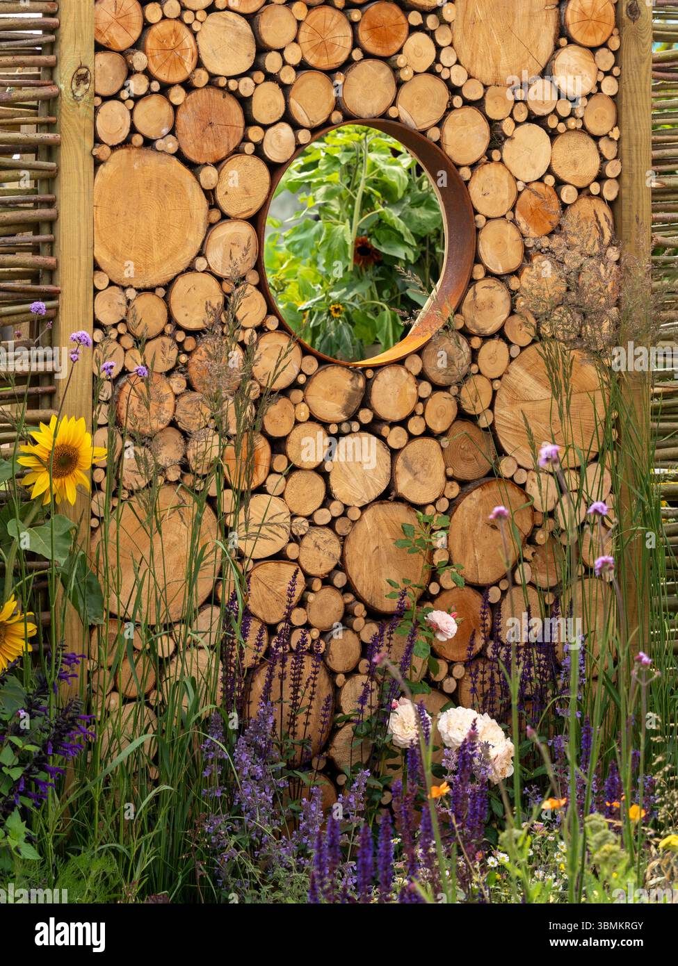 Vagliatura da giardino realizzata con tronchi di legno segati con apertura circolare, bordati in acciaio resistente agli agenti atmosferici. Foto Stock