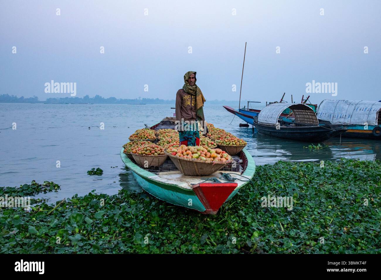 Gli agricoltori scaricano verdure invernali dalle barche al mercato di Baishmouja lungo il fiume Meghna a Nabinagar, nel distretto di Brahmanbaria, Bangladesh. Foto Stock