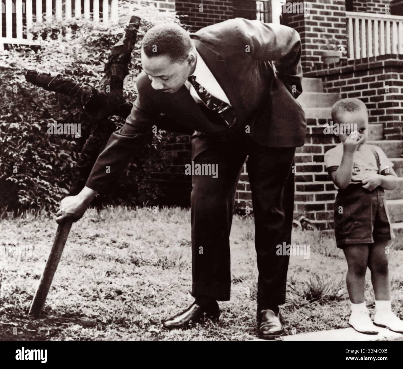 Martin Luther King Jr. (Con il suo giovane figlio in piedi accanto a lui) tirando una croce che fu bruciata dal Ku Klux Klan il 25 aprile 1960, sul prato anteriore della sua casa di Atlanta. La residenza del re era una delle numerose case nere prese di mira dal Klan. (USA) Foto Stock