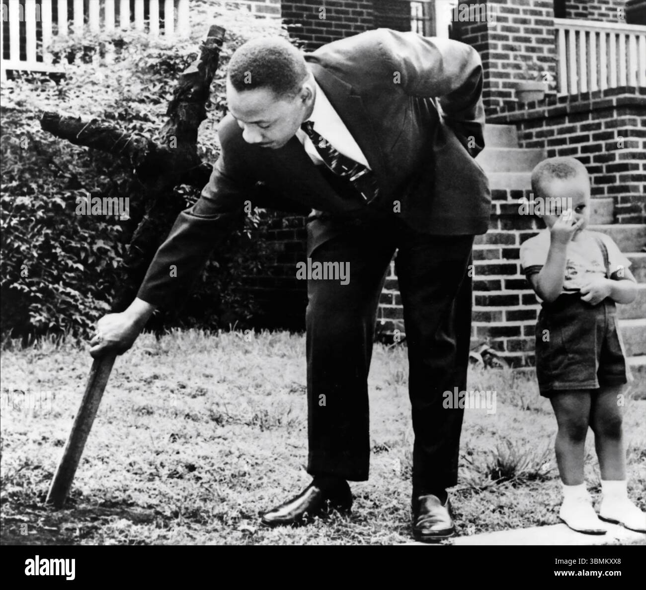 Martin Luther King Jr. (Con il suo giovane figlio in piedi accanto a lui) tirando una croce che fu bruciata dal Ku Klux Klan il 25 aprile 1960, sul prato anteriore della sua casa di Atlanta. La residenza del re era una delle numerose case nere prese di mira dal Klan. (USA) Foto Stock