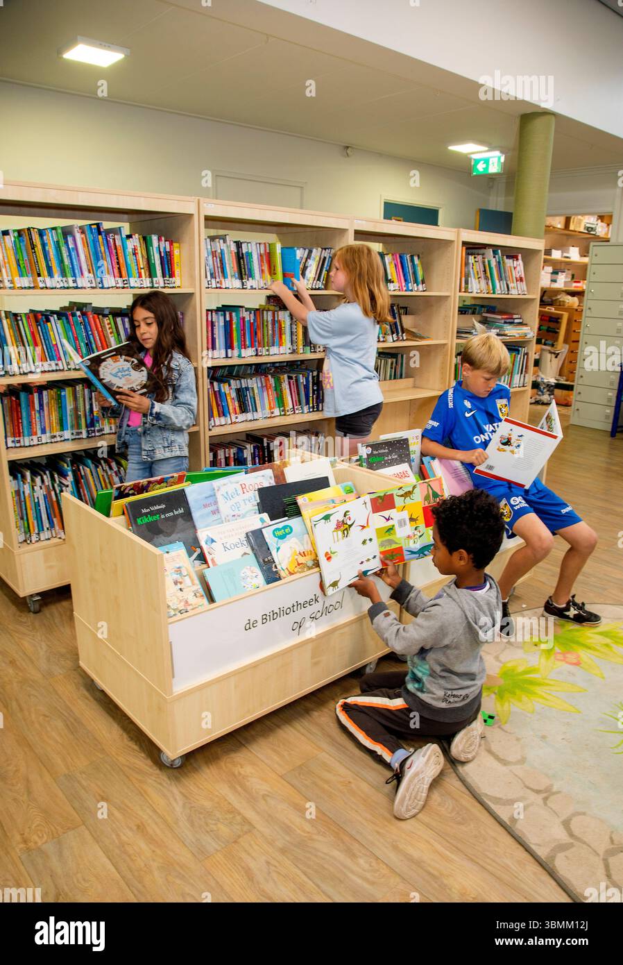 Paesi Bassi - bambini che cercano un libro e leggono libri nella biblioteca della loro scuola primaria. Foto Stock