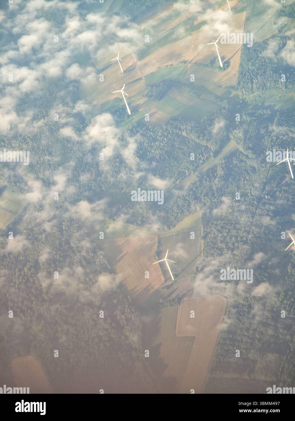 Un gruppo di turbine eoliche è visibile nel cielo. Le turbine eoliche sono distribuite e si trovano in un campo Foto Stock