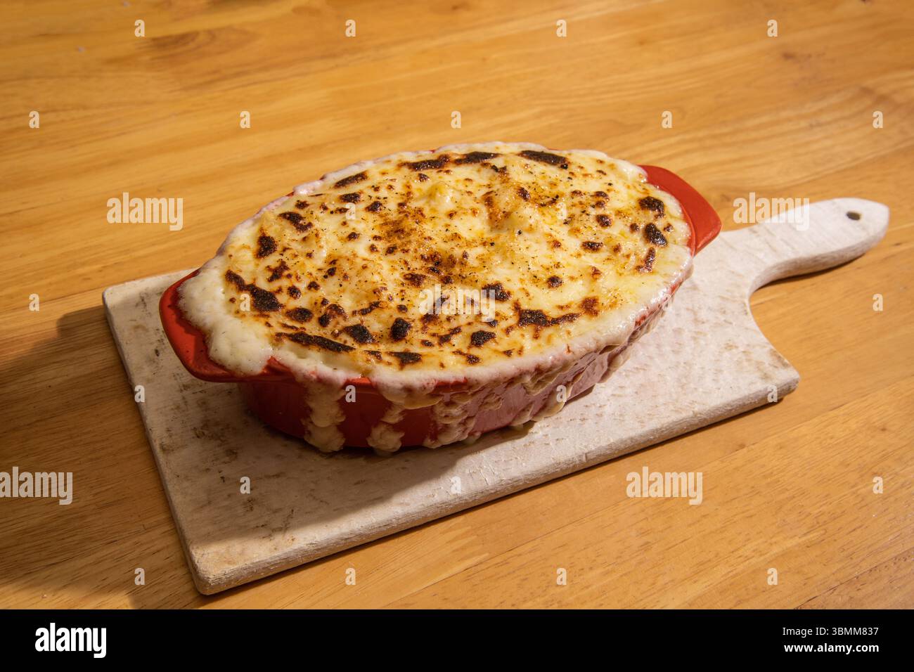Formaggio macaroni appena sfornato in un piatto arancione da forno, top croccante dorato direttamente dal forno Foto Stock