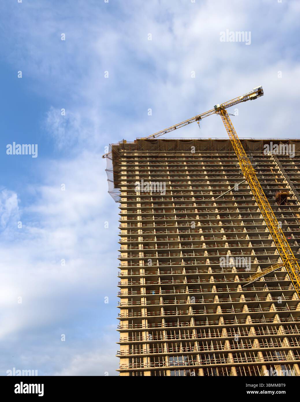 Alto edificio in costruzione con gru a torre a Batumi, Georgia. Moderna scena urbana contro il cielo nuvoloso. Solo per uso editoriale. Foto Stock