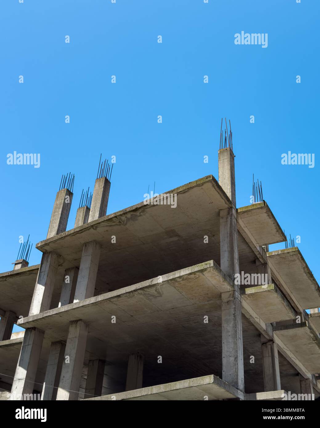 Edificio in cemento non finito con armature esposte a Batumi, Georgia. Scena di costruzione urbana sotto il cielo blu. Solo per uso editoriale. Niente persone. Foto Stock