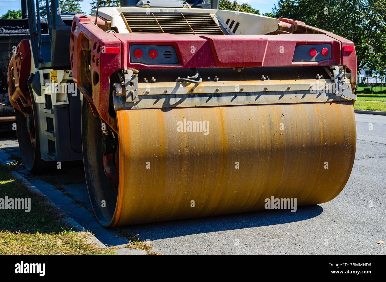 Ruggine grande rullo anteriore su un compattatore vibrante parcheggiato in una strada cittadina di giorno. Foto Stock