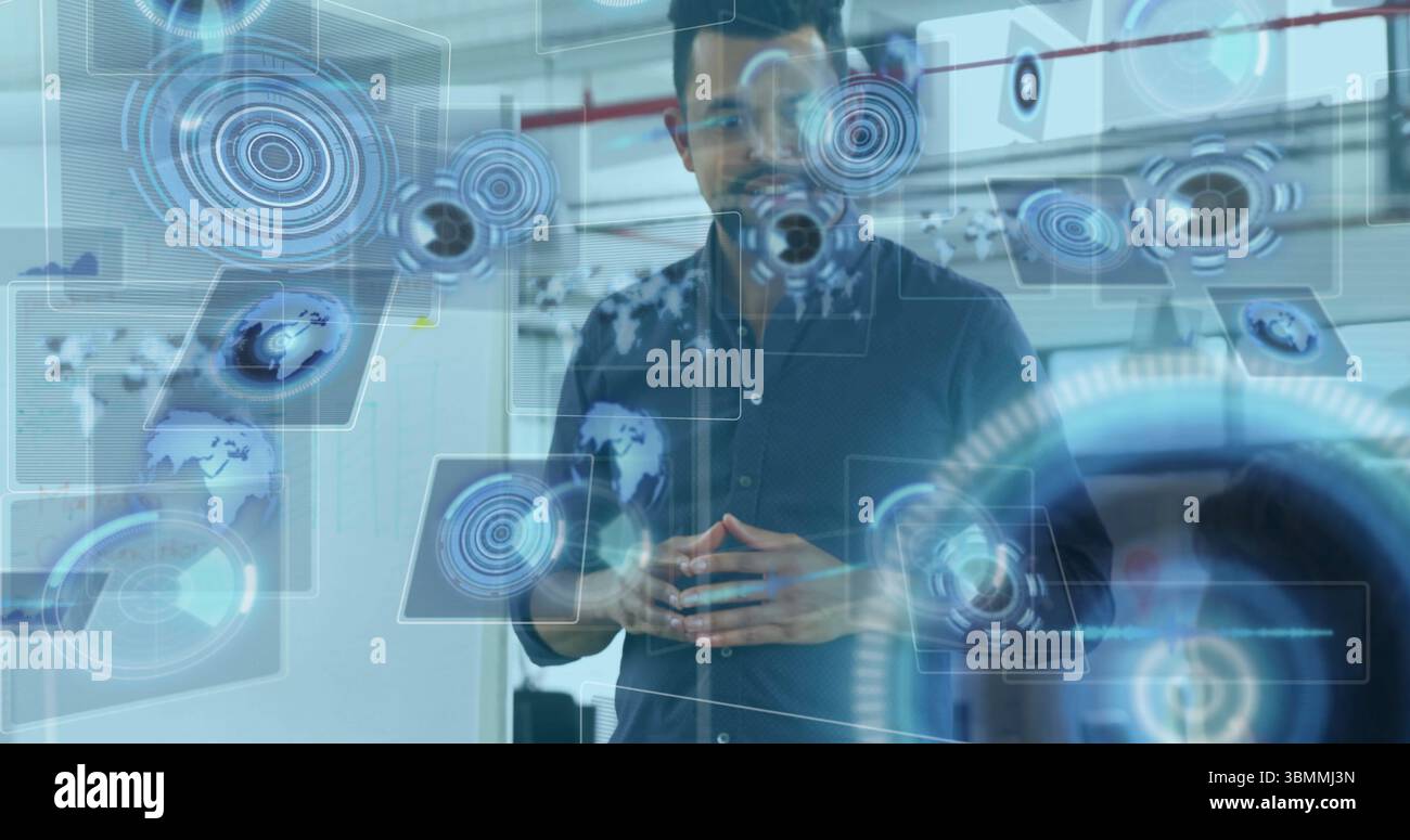 Uomo in piedi dell'Asia meridionale che interagisce con l'interfaccia utente olografica nel laboratorio tecnico, con sovrapposizione dei dati Foto Stock