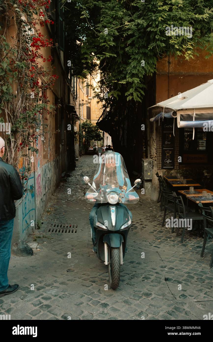 Roma, Italia, Scooter che attraversa il quartiere di Trastevere. I turisti si riversano in questa zona Foto Stock