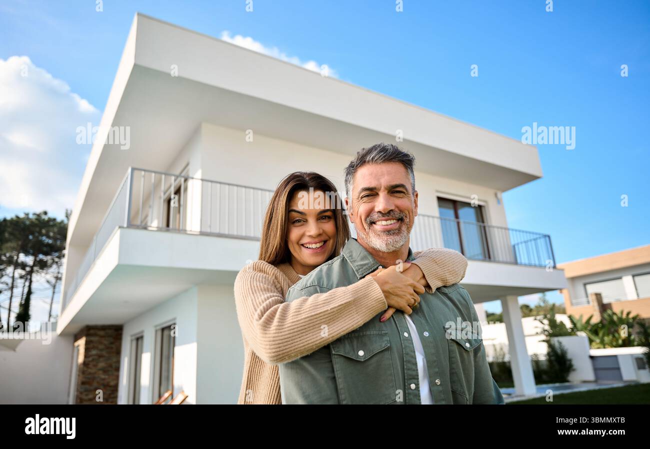 Felice sorridere la coppia di anziani nuovi proprietari di case in piedi fuori casa. Foto Stock