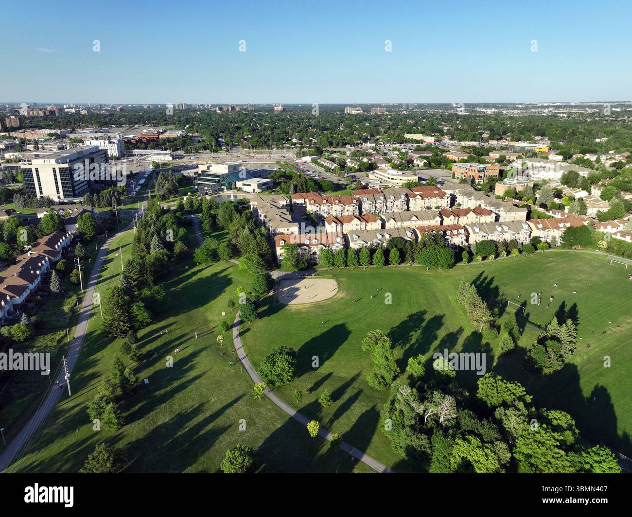 Un esteso paesaggio urbano e suburbano presenta aree residenziali, edifici commerciali e spazi verdi che si estendono verso un lontano skyline della città Foto Stock