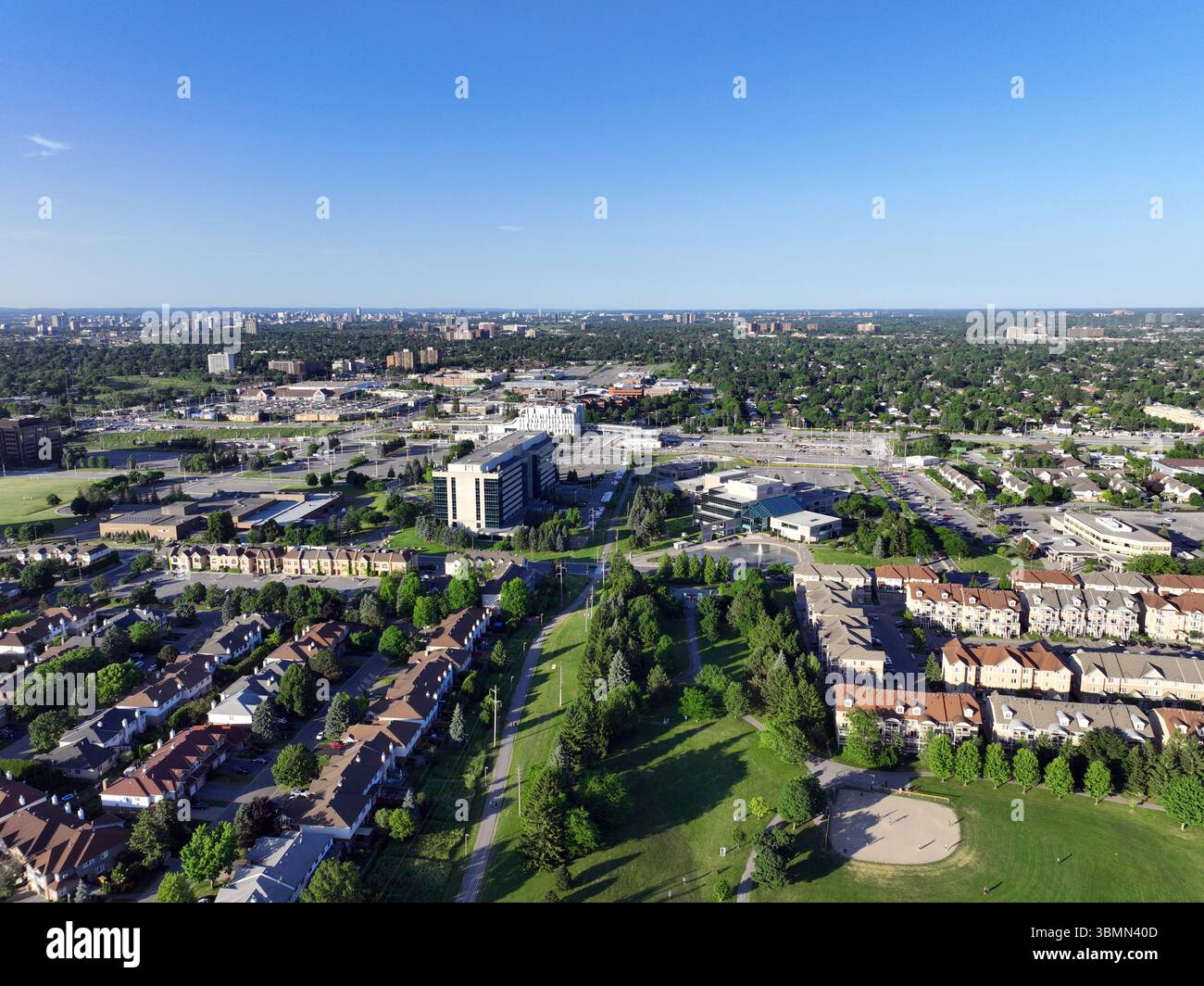 Un esteso paesaggio urbano e suburbano presenta aree residenziali, edifici commerciali e spazi verdi che si estendono verso un lontano skyline della città Foto Stock