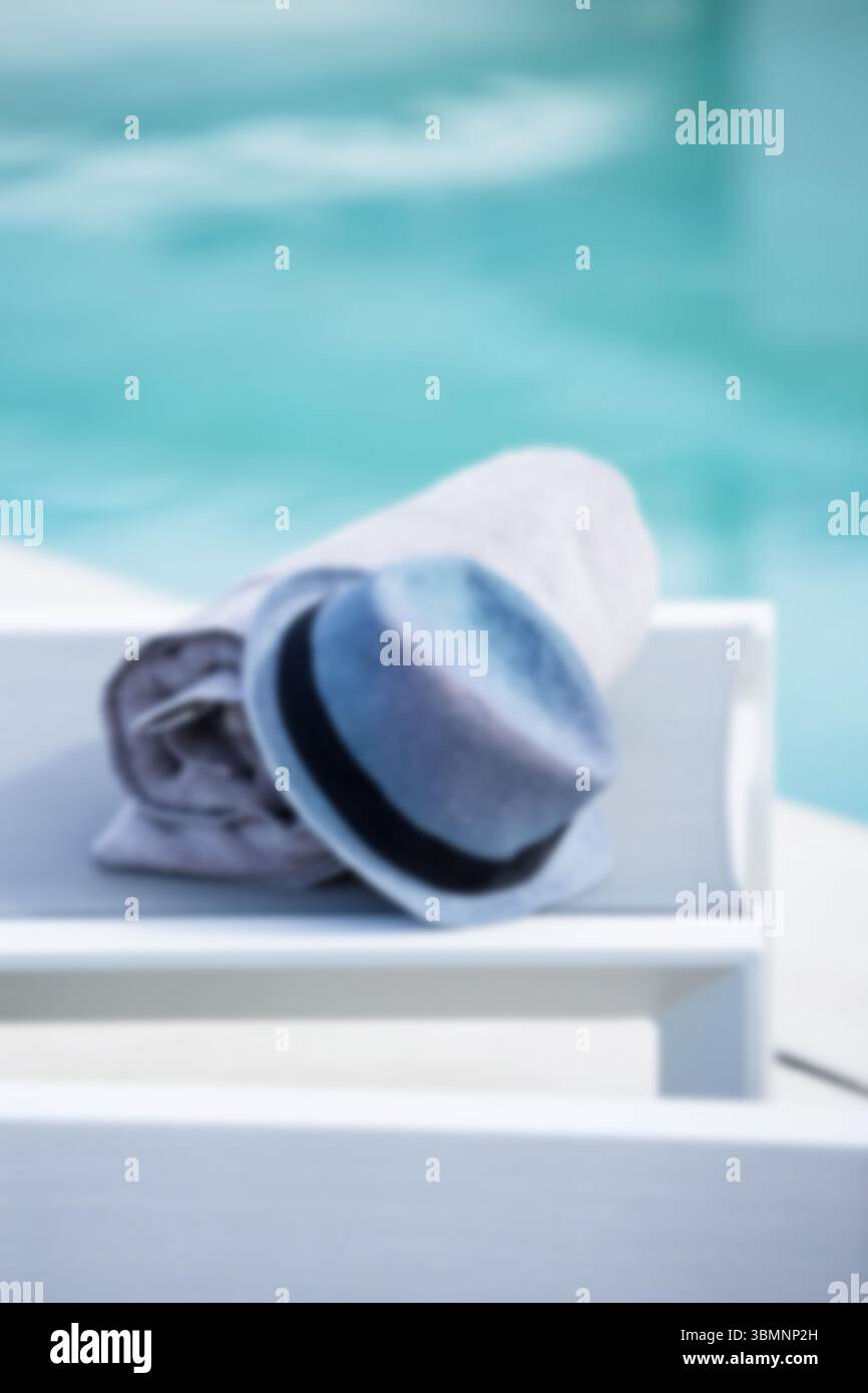 Asciugamano e cappello sul tavolo a bordo piscina Foto Stock