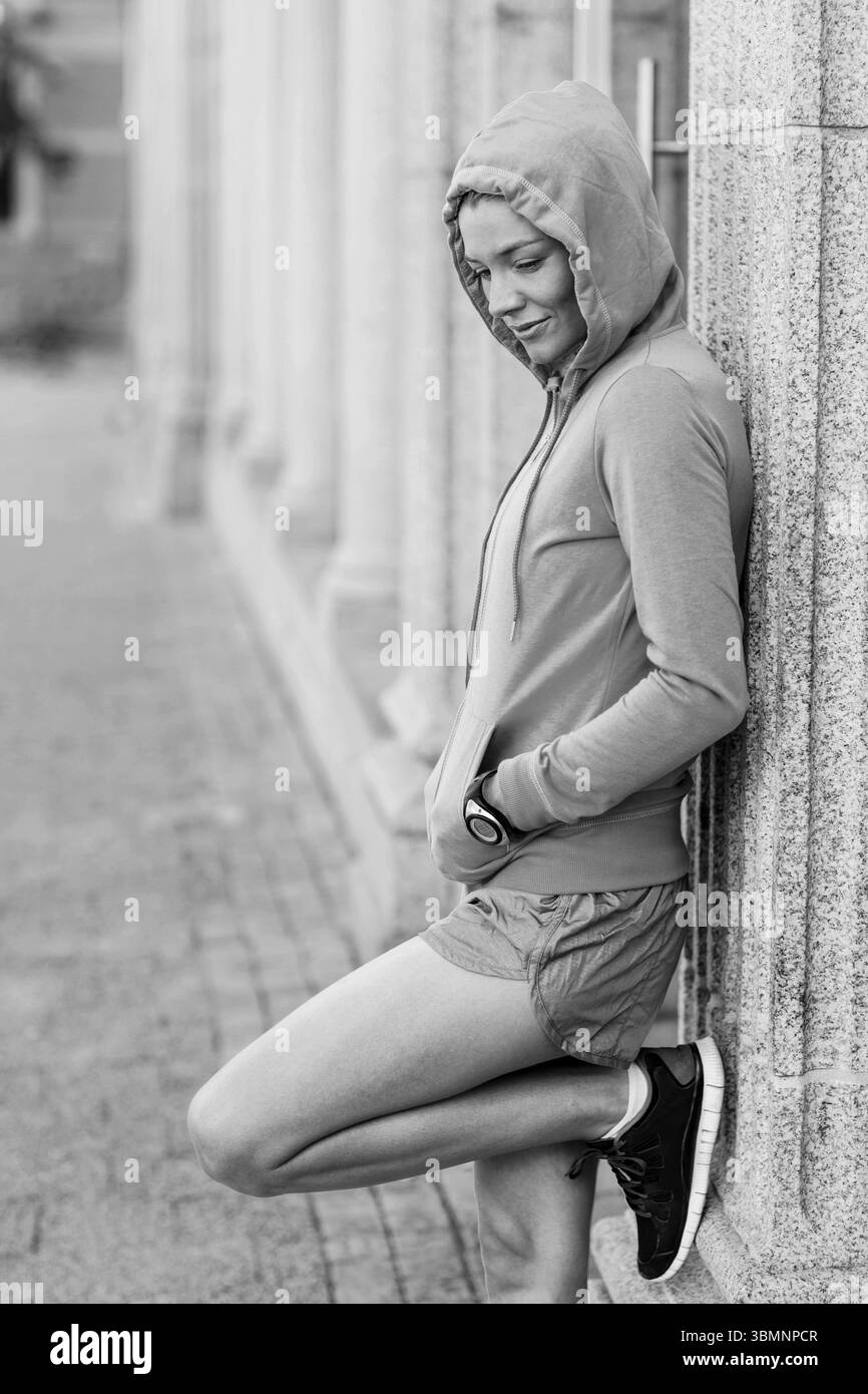 Premurosa donna appoggiata sulla parete Foto Stock