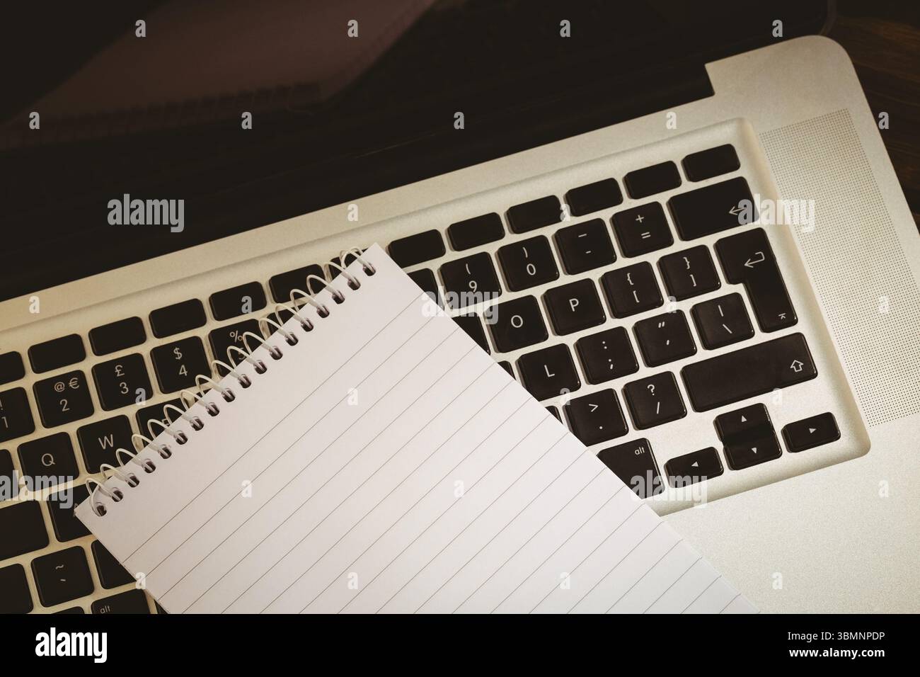 l'arte del design piatto mostra un notebook a spirale vuoto diagonalmente sulla tastiera del computer portatile su una scrivania in legno Foto Stock