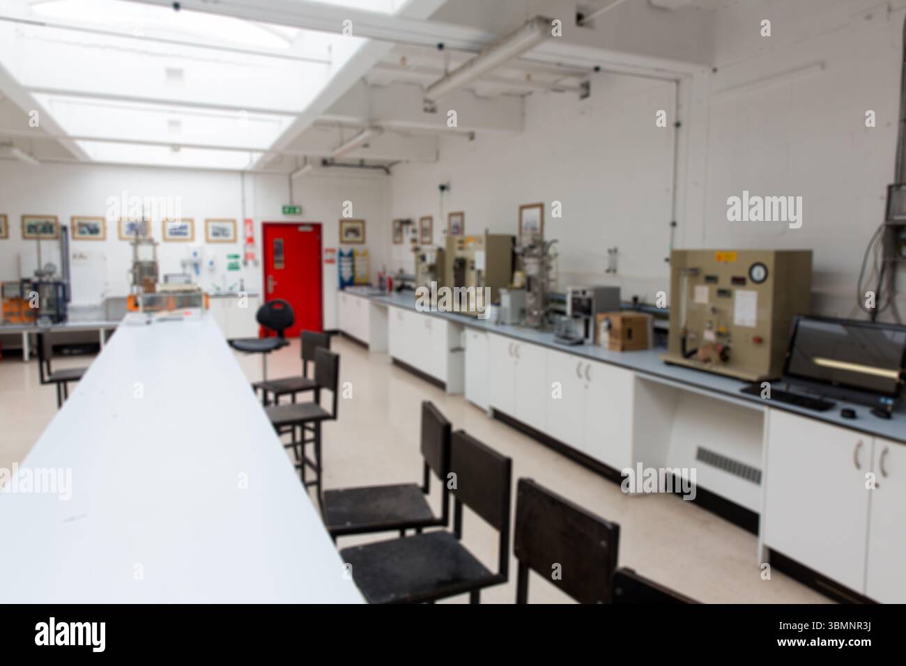 Banco da laboratorio bianco lungo con sgabelli neri, che copre il laboratorio di progettazione piatto e mostra gli strumenti Foto Stock