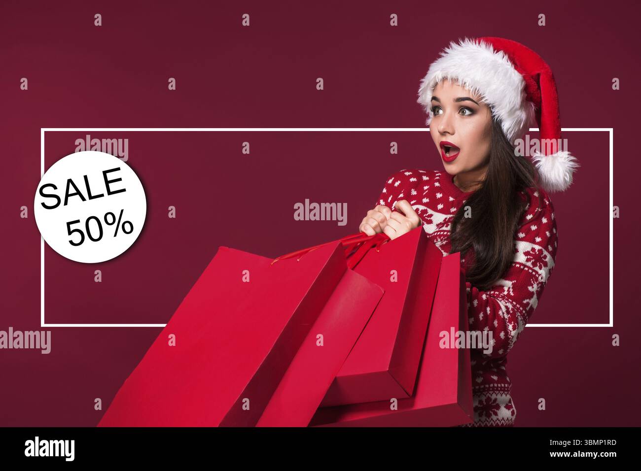 Donna di natale. Modello di bellezza ragazza in santa hat su sfondo rosso. Divertente ridere sorpreso ritratto di donna. A bocca aperta. Emozioni vere. Labbra rosse e essere Foto Stock