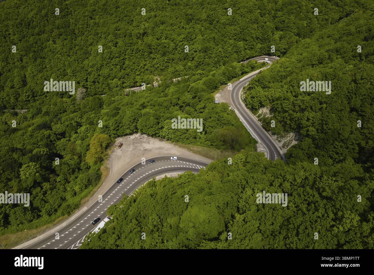 Vista aerea della strada tortuosa dall'alto passo di montagna. Ottimo viaggio in auto attraverso i fitti boschi. Vista a volo d'uccello Foto Stock