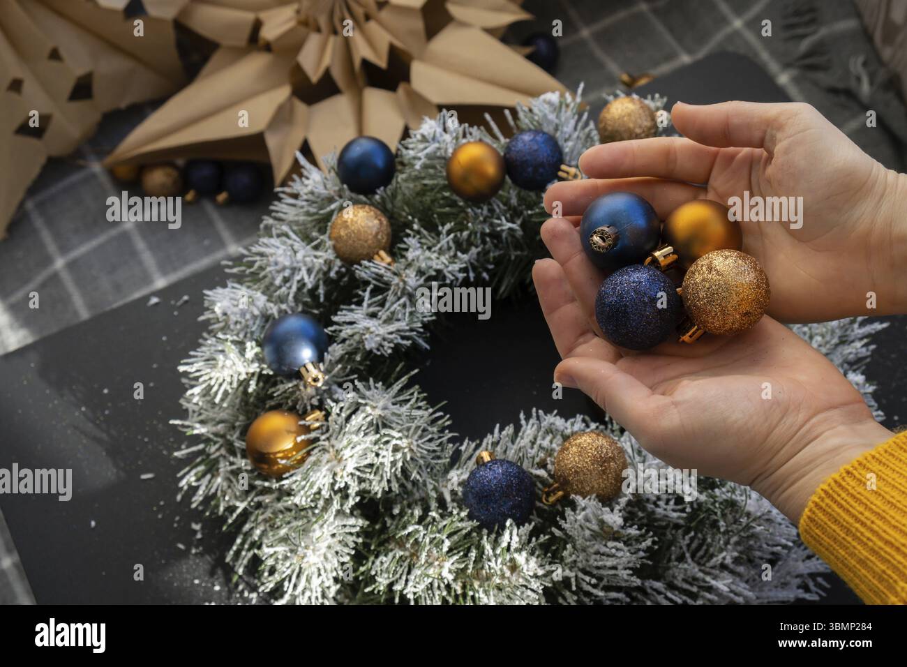 Corona di Natale realizzata a mano con decorazioni festose blu e gialle. Preparazione per le festività natalizie, maestria nella creazione creativa dell'arredamento. Pratica Foto Stock
