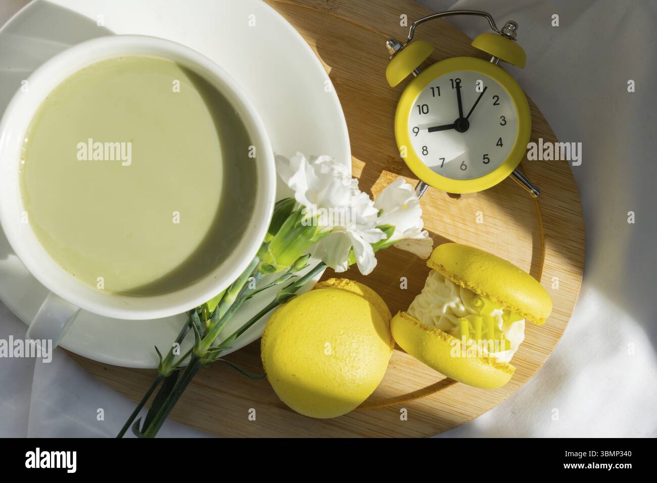 Sveglia gialla sveglia dolce dolce dessert di macaron giallo tazza di tè matcha e latte a base di piante verdi in un'atmosfera accogliente da letto mattutina. Holida creativa Foto Stock