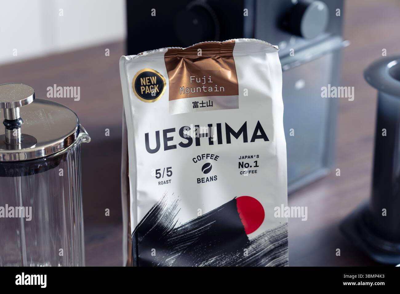 Pacchetto di chicchi di caffè tostato scuro di Fuji Mountain Ueshima su una superficie della cucina con attrezzatura per la preparazione del caffè, dichiarato come il marchio di caffè numero uno del Giappone Foto Stock