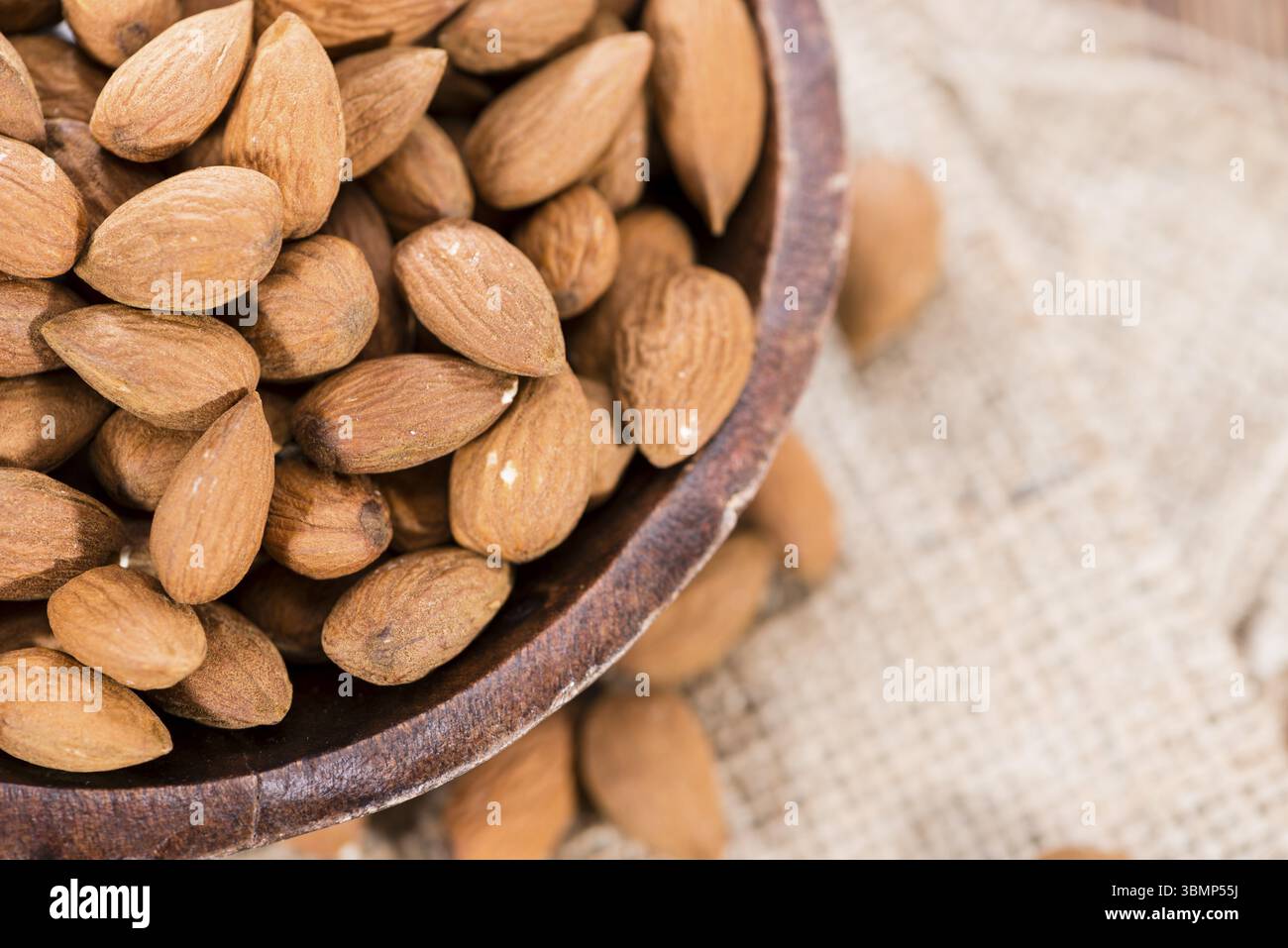 Porzione di mandorle essiccate (close-up shot) su sfondo di legno Foto Stock